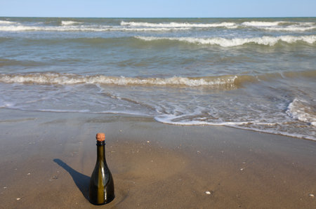 beached green glass bottle with a message inside on the foreshore near the beachの写真素材