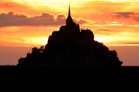 Romantic Red sunset and silhouette of the island of Mont Saint Michel in Franceの写真素材