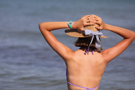 young girl with big straw hat by the sea during summer vacation