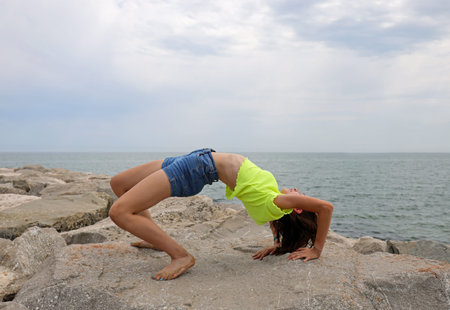 young girl performs gymnasyoung girl performs gymnastic exercises arching her back backwards on the...