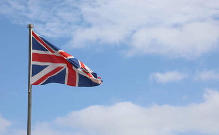 united kingdom flag on the blue sky and some white cloudsの写真素材