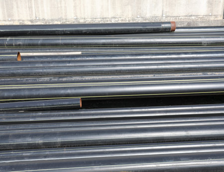 black plastic pipes in the deposit of building material on the road construction site