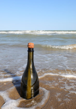 beached green glass bottle with a message inside on the foreshore near the beachの写真素材