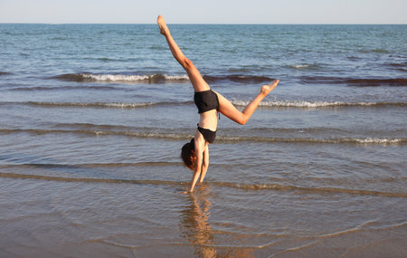 slim athletic girl performs gymnastic exercises in summer