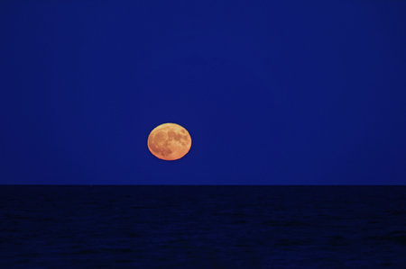 red full moon over the calm evening sea