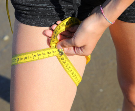 measurement of the circumference of the leg of girl with tape measure and measures in centimeters
