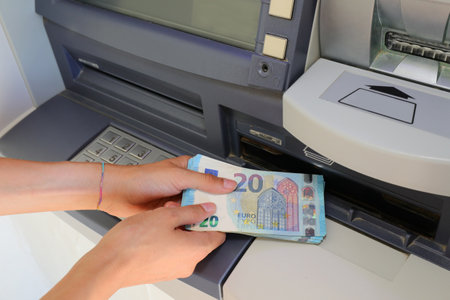 hand picking up money in European banknotes from an ATM bank cash machine in Europeの写真素材