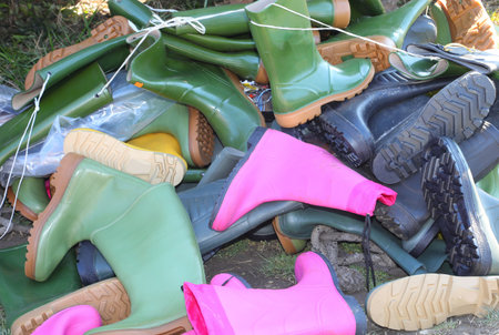 pile of many rubber boots for sale in used and new goods storeの写真素材