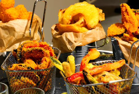 trays of mixed fried vegetables with battered and french fries for sale in the street food stallの写真素材