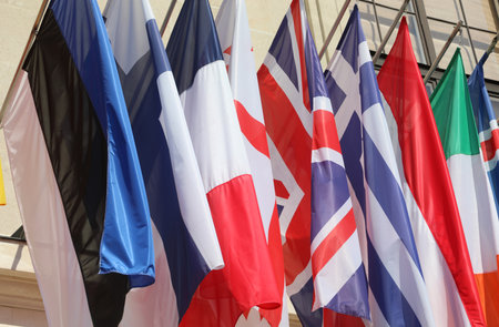 colorful flags of many world nations hanging outside government building with no peopleの写真素材