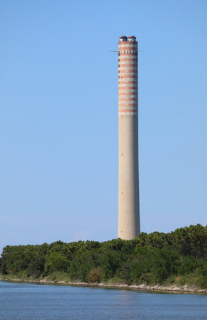 Porto Tolle, RO, Italy - July 5, 2023: Big chimney of a thermoelectric plant near water of Po Riverのeditorial素材