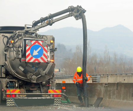 large truck with hose for maintenance of motorways and highways and the operator at workの写真素材