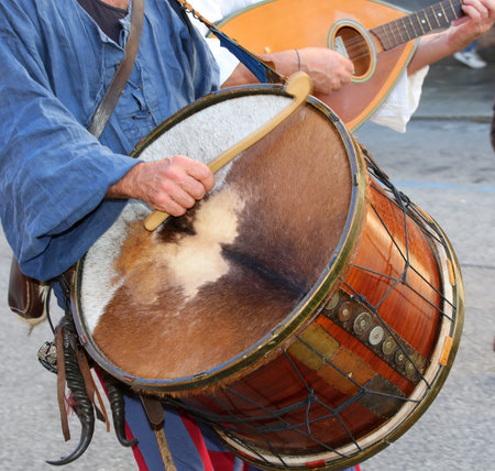old drummer plays an ancient drum made from animal skins and medieval clothes