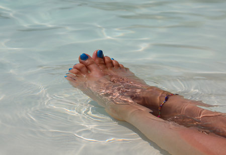 Legs on girl with toenails colored with nail polish relaxes inside the waterの写真素材