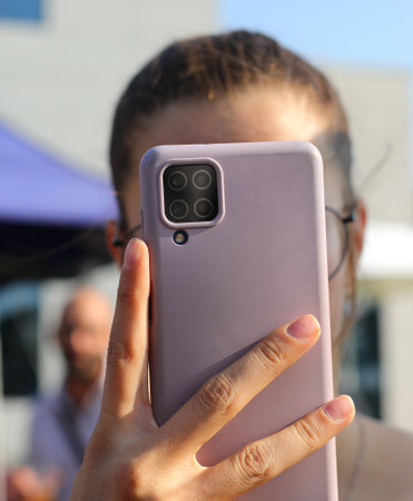 young influencer girl recording a video with modern smartphone in her hand in the cityの写真素材