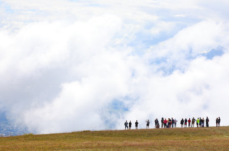 silhouettes of many people and wide panoramic view of white clouds in mountainの写真素材