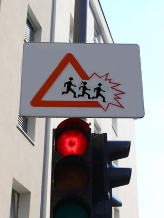 red traffic light and attention road sign at school with children running and going off the edge very funnyの写真素材