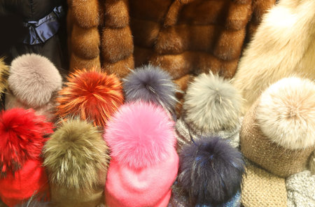 many colorful fashionable hats and caps with fur fur for sale in the window of winter clothing boutiqueの写真素材