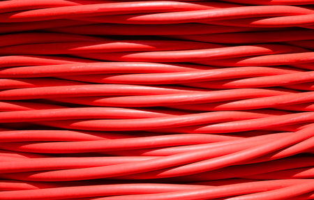 background of detailed thick red electrical cable used for high voltage power transmission from a...