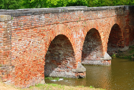 Ancient bridge made of red bricks with three arches over the riverの写真素材