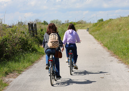 young girl with her mother cycling in the cycle path during the outdoor excursionの写真素材