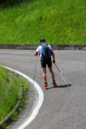 skier with ski Roller on asphalt road and poles for training during summer seasonの写真素材