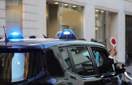 Police car with blue lights flashing and officer using siren during a chase in the cityの写真素材