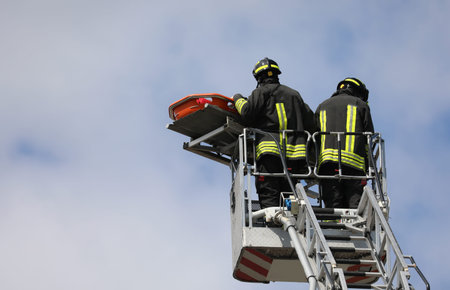 Two firefighters in the basket of the aerial ladder of fire truck during the rescue of the injured...