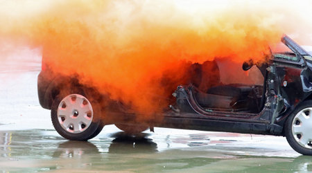 completely destroyed car with orange smoke bomb targeted by vandals during the riot in the cityの写真素材