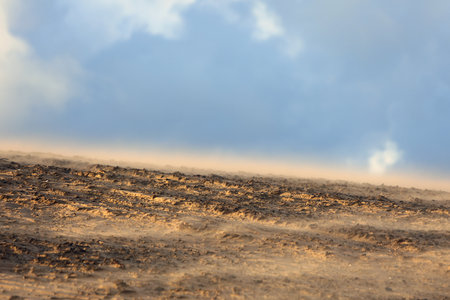Sand dunes moved by the wind in the desert and the white clouds on the horizon without peopleの写真素材