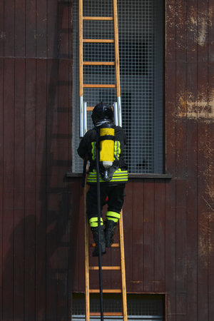 firefighter wearing an oxygen tank climbs a ladder during a training exercise at the fire barracksの写真素材