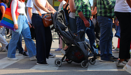 Busy people rushing while a mother pushes a baby stroller across a crosswalk