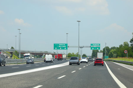 Motorway junction in ITALY called PASSANTE DI MESTRE with road signs to Trieste Belluno Venice and the direction towards Venetian airport and many carsの写真素材