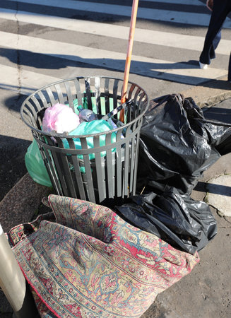 urban bin full of garbage bags and even an old worn out carpet thrown in the garbage without any civilityの写真素材