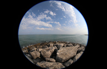 Fisheye lens view of the sea and rocks with a dark vignette caused by the special type of lens creating a viewfinder effectの写真素材