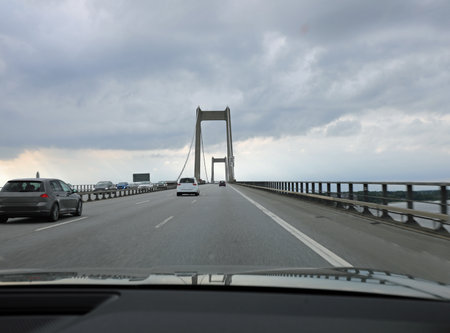 multi-lane highway with cars speeding over a suspension bridge and the massive concrete pillar while travelingの写真素材