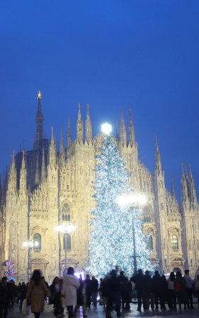 Gothic facade of Milan Cathedral and people during Christmas holidays with the huge Christmas treeの写真素材