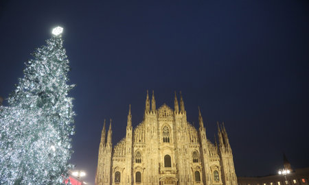 milan cathedral s gothic facade shines bright with festive christmas tree and glowing snowflake topperの写真素材