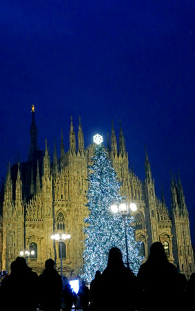 facade of Milan Cathedral and silhouettes of people during Christmas holidays with the huge Christmas treeの写真素材