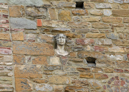 Ancient woman face called Berta embedded in the ancient tower of the medieval building in Florence central Italy in Region Tuscanyの写真素材