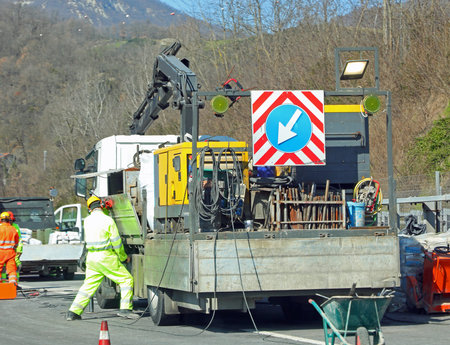 road construction site with the truck and arrow and cones to reduce lanes and workers at work in...