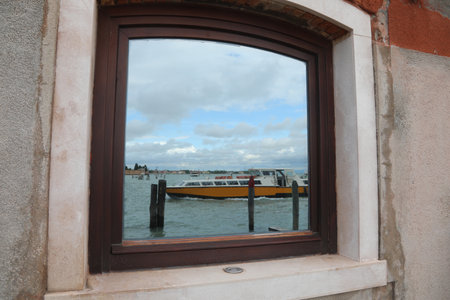 Boat mirrored in the glass of window on Venice Island in Italyの写真素材