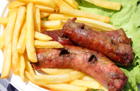 grilled pork sausages with lots of crispy yellow fries on lettuce green leaf