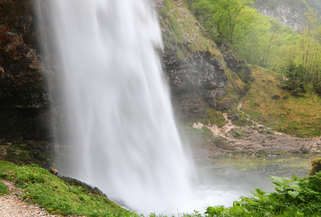 waterfall with lots of water and sprays in an unspoilt environment in the mountainsの写真素材