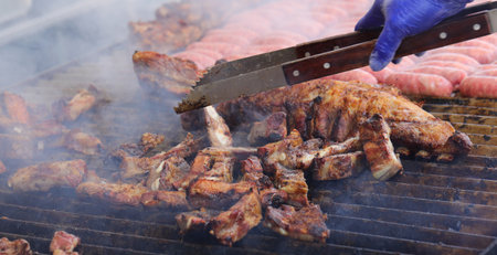 the cook with the latex blue glove that cooks the hot grilled meat of the restaurantの写真素材