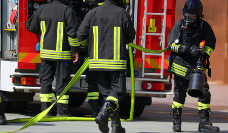 fire brigade in uniform during an emergency and red fire truckの写真素材