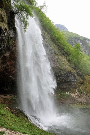 very high waterfall with sparkling white foam that can be seen from the rocks above and forms a small pondの写真素材