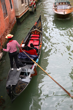 Expert Gondolier with red and white jersey on the Gondola Boat in Venice Island in Northern Italyの写真素材