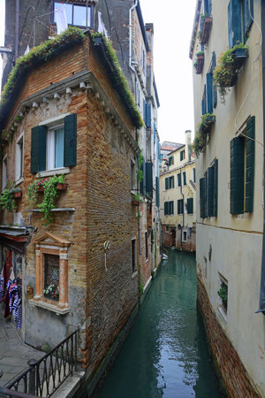 Corner of old palace in red bricks and the navigable waterway and more Venetian houses in Venice in Northern Italyの写真素材