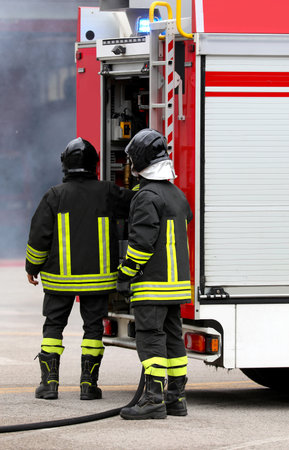 Two firefighters preparing and using the safety devices and the pump truckの写真素材